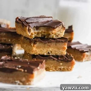 A stack of three millionaire's shortbread bars on parchment paper with the top one missing a bite.