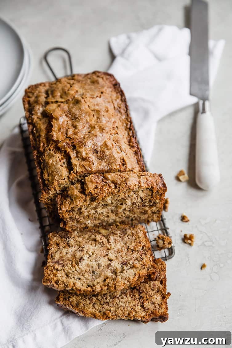 A loaf of banana bread on a wire rack with a few slices cut off, ready to be enjoyed.