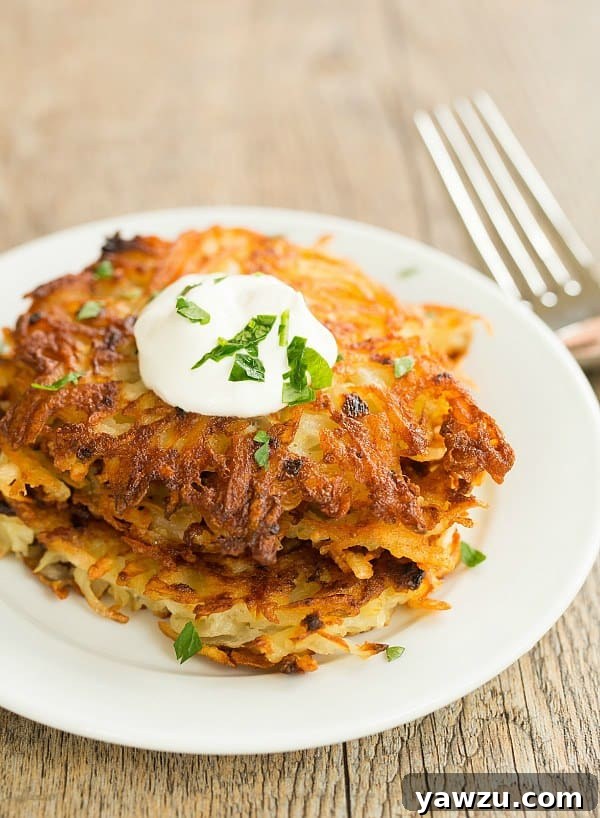 Freshly fried crispy potato latkes neatly stacked on a plate, ready to be served.
