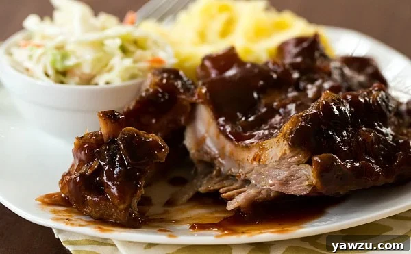 Close-up of tender Slow Cooker BBQ Ribs on a plate with sauce.