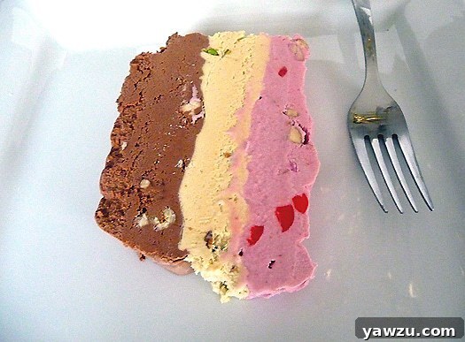 Slice of spumoni ice cream terrine on a white plate with a fork.