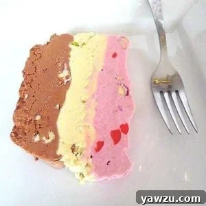 Slice of spumoni ice cream terrine on a white plate with a fork.