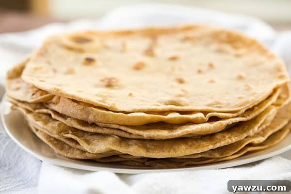 Freshly rolled homemade flour tortilla dough on a floured surface, ready for cooking.