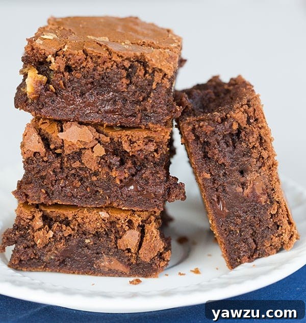 Close-up of a brownie with a crisp, crackly top and visible chocolate chips.