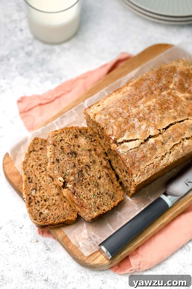 Overhead photo of zucchini bread on cutting board with two pieces sliced off, showcasing its moist texture and golden-brown crust.