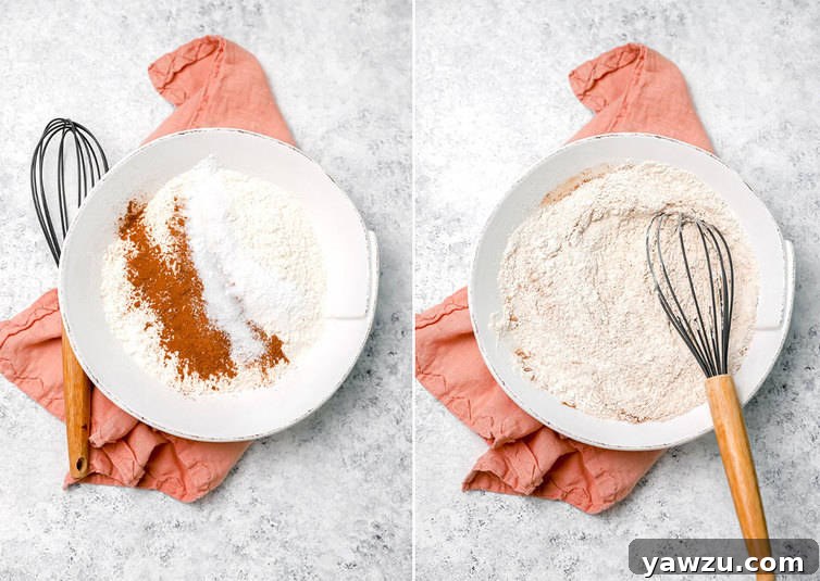 A person whisking together dry ingredients like flour, cinnamon, baking powder, baking soda, and salt in a large mixing bowl for zucchini bread preparation.
