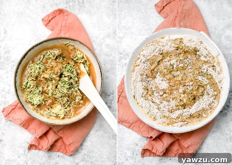 A rubber spatula gently folding the wet zucchini mixture into the dry flour mixture in a large bowl, combining them to form the zucchini bread batter.