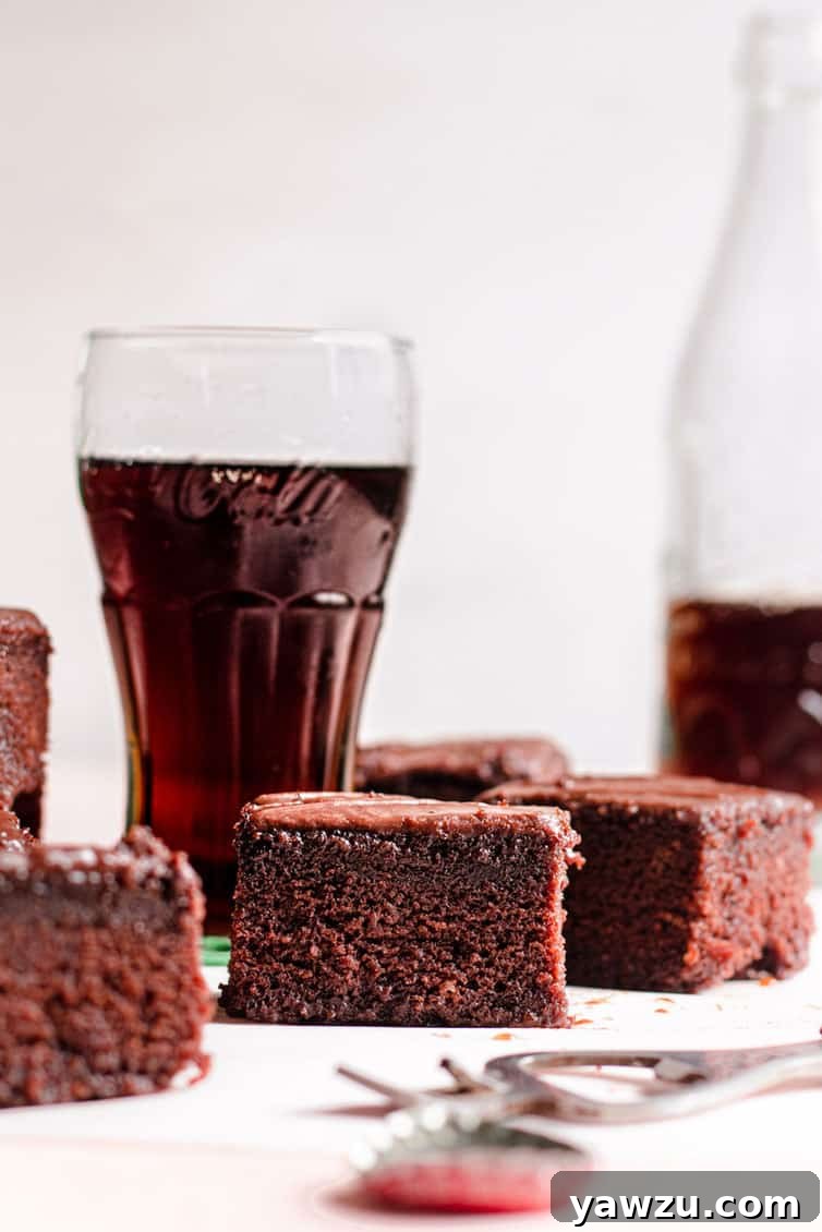 Pieces of chocolate cake in front of glasses of Coca Cola.