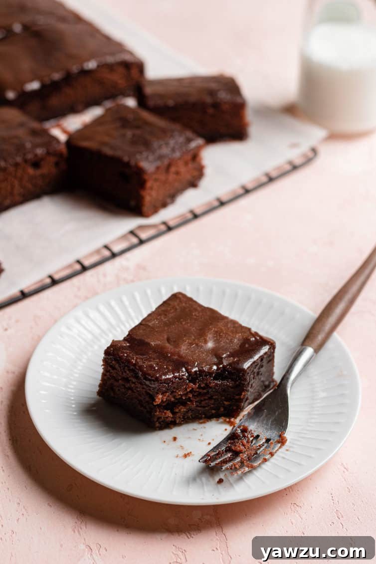A slice of coca cola cake on a plate with a fork.