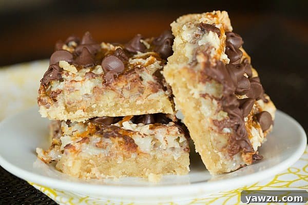 Freshly baked Ultimate Magic Bars cooling on a wire rack, showing off their rich layers of chocolate, caramel, pecans, and coconut over a golden shortbread crust. Ready to be sliced and enjoyed!
