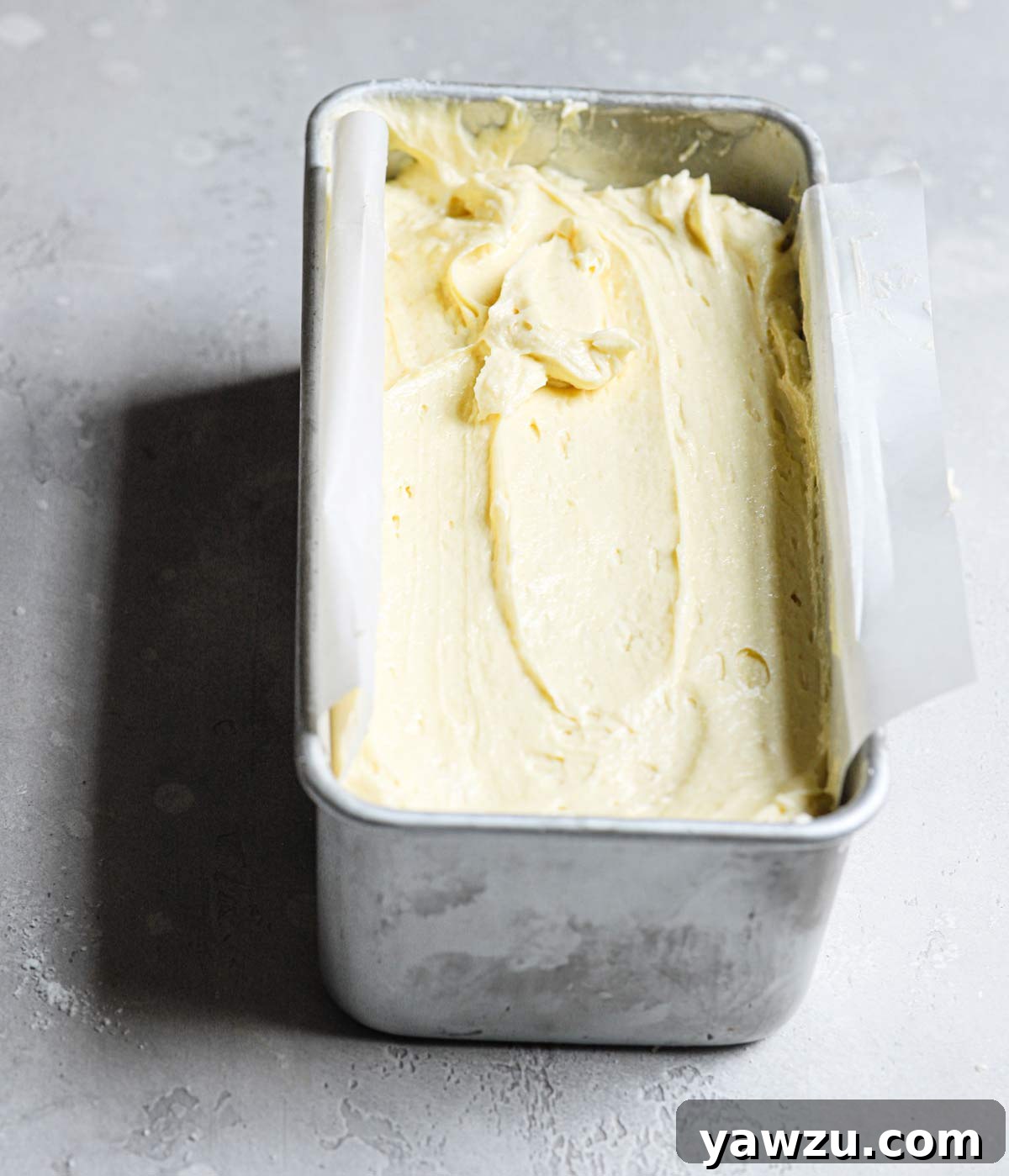 Pound cake batter in a silver loaf pan.