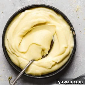 Top down photo of a black bowl with pastry cream and a silver spoon scooping pastry cream in the bowl.