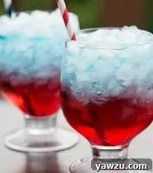 A tall glass showcasing a Red, White & Blue Layered Drink, garnished and ready to serve.
