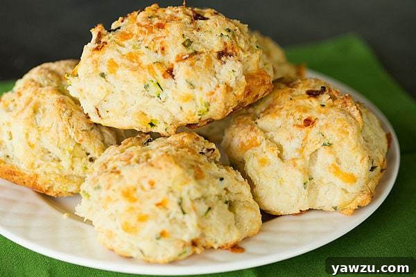 Close-up of freshly baked Cheesy Zucchini and Sun-Dried Tomato Scones on a baking sheet.