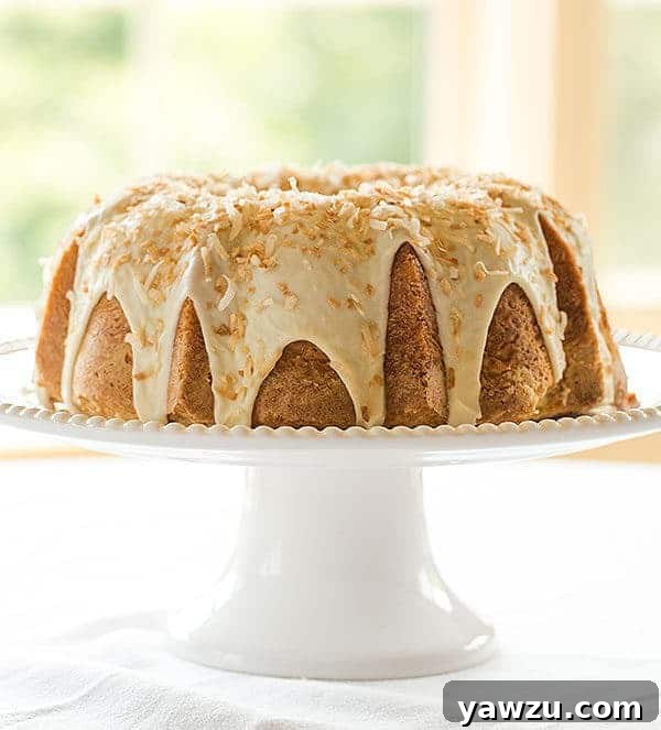 Close-up of a slice of moist Coconut Bundt Cake, revealing its rich texture and glossy white chocolate-coconut glaze