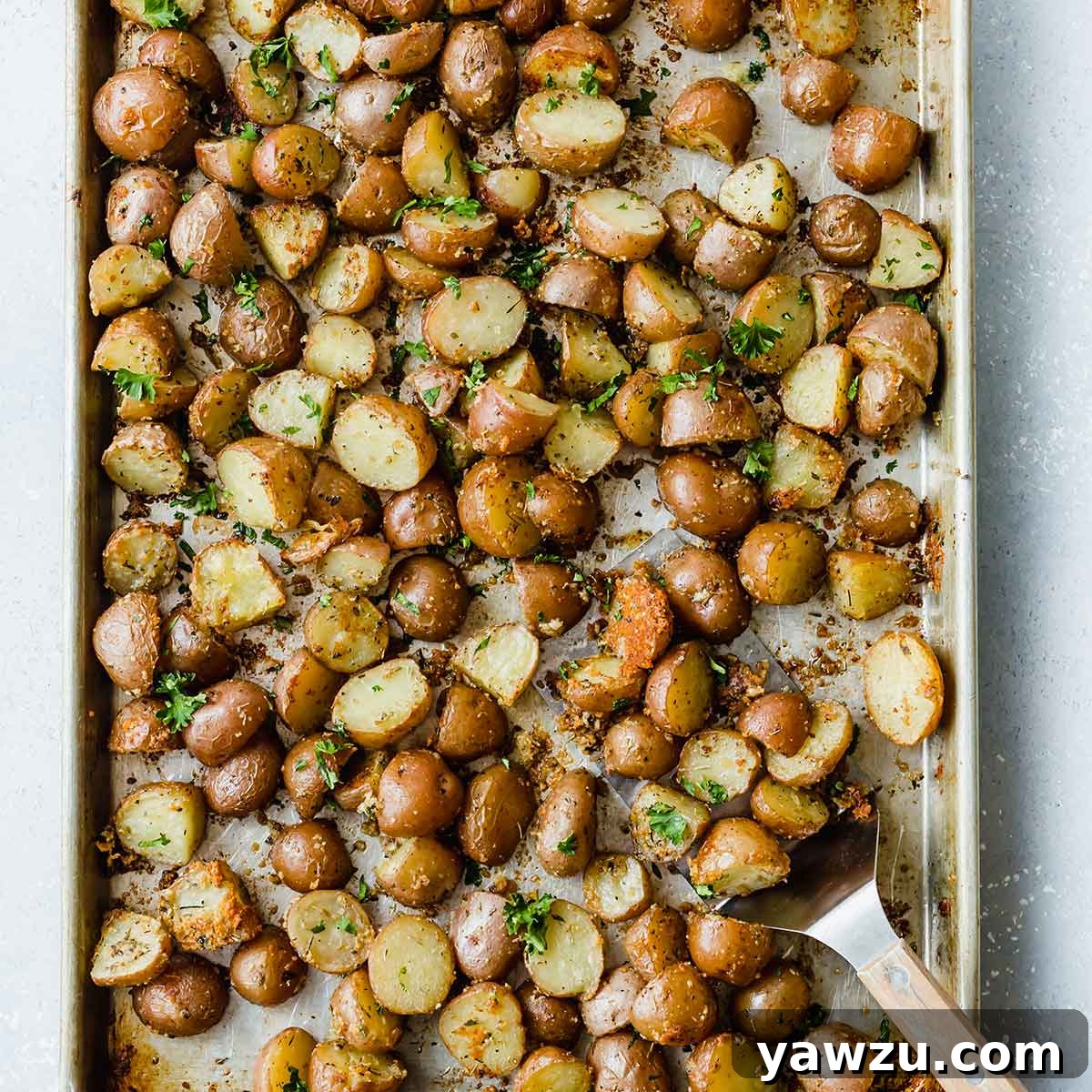 A sheet pan generously filled with an abundant serving of golden-brown and crispy roasted red potatoes, fresh from the oven.