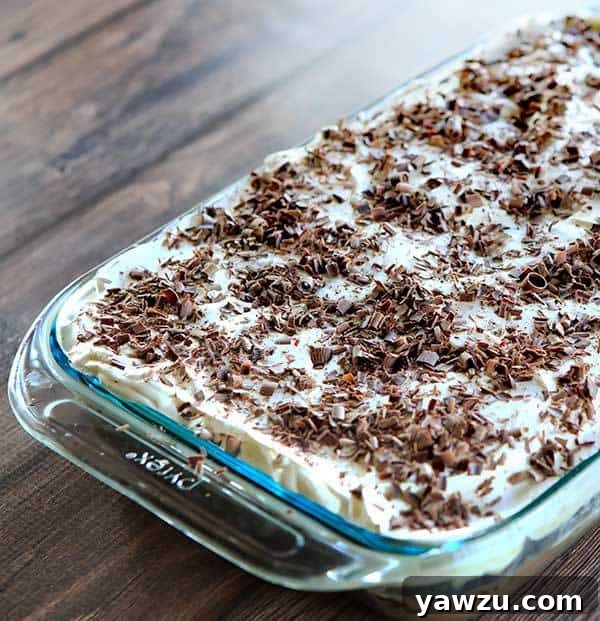 Close-up of a slice of Mudslide Poke Cake, showcasing the rich chocolate layers, the generous infusion of the mudslide mixture, and the fluffy whipped topping. A truly decadent and easy-to-make dessert for chocolate and cocktail lovers. | browneyedbaker.com