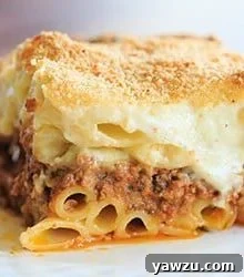 A serving of Pastitsio, showing the golden béchamel, tubular pasta, and rich meat filling.