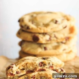 One chocolate chip cookie split in half in front of a stack of cookies.