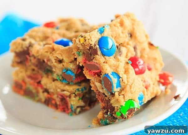 A close-up shot of a single Monster Cookie Bar, showcasing its thick, rustic texture and the generous distribution of M&M's and chocolate chips.