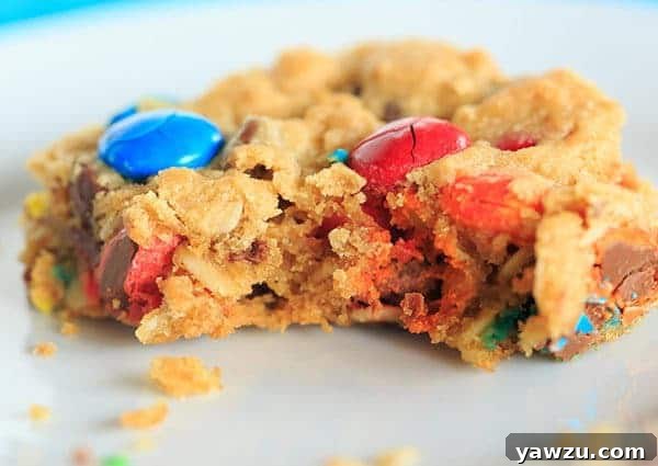 Several Monster Cookie Bars stacked, showing their uniform shape and the tempting array of chocolate and candy in each layer.