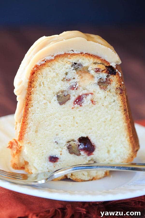 Delicious Cranberry-Pecan Pound Cake with Praline Frosting on a white cake stand, ready for slicing