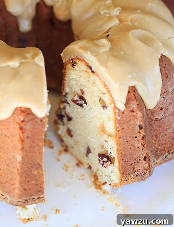 Sliced Cranberry-Pecan Pound Cake with praline frosting on a serving plate, showing moist interior