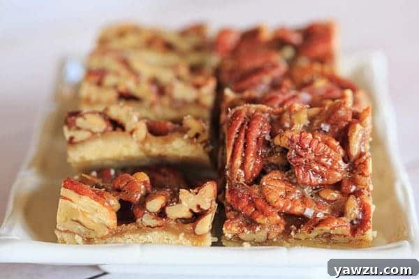 Close-up view of a single Ultranutty Pecan Bar, showing its crispy edges and generous, glistening pecan topping