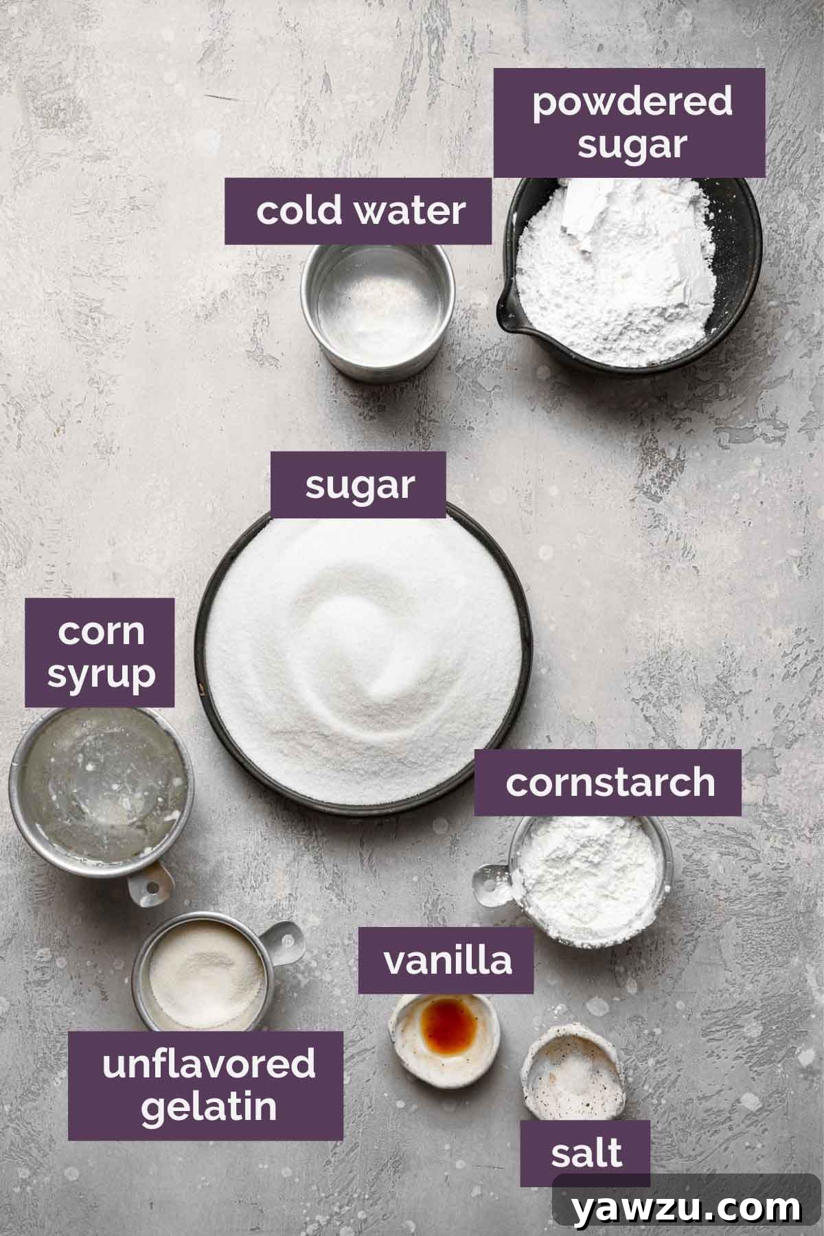 Ingredients for homemade marshmallows prepped and labeled: powdered sugar, cold water, granulated sugar, corn syrup, cornstarch, vanilla extract, unflavored gelatin, and salt, neatly arranged on a white surface.