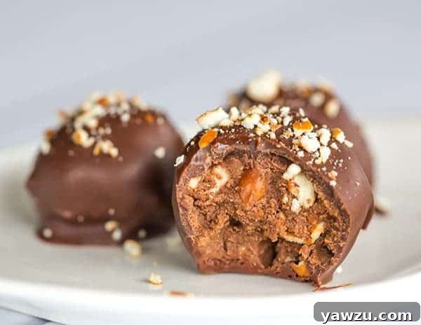 A small stack of perfectly coated Nutella Pretzel Truffles, garnished with extra pretzel crumbs for added texture and visual appeal.