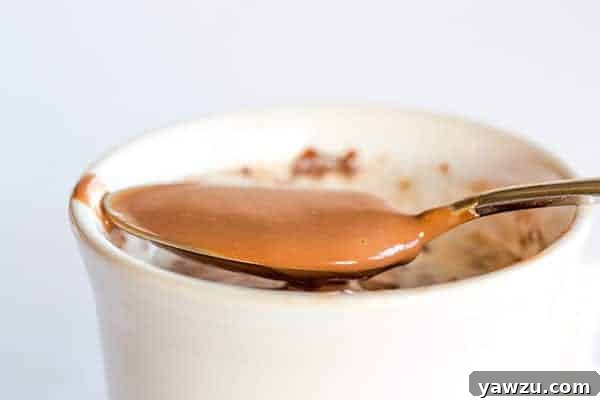 Italian Hot Chocolate (Cioccolata Calda) - A single mug of hot chocolate with whipped cream and a small spoon, emphasizing its drinkable pudding-like quality.