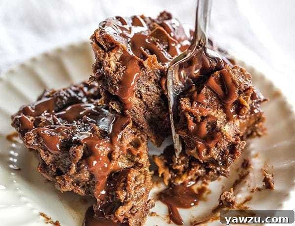Portion of chocolate bread pudding served on a white plate, garnished with chocolate drizzle and a fresh sprig of mint, ready to be enjoyed.