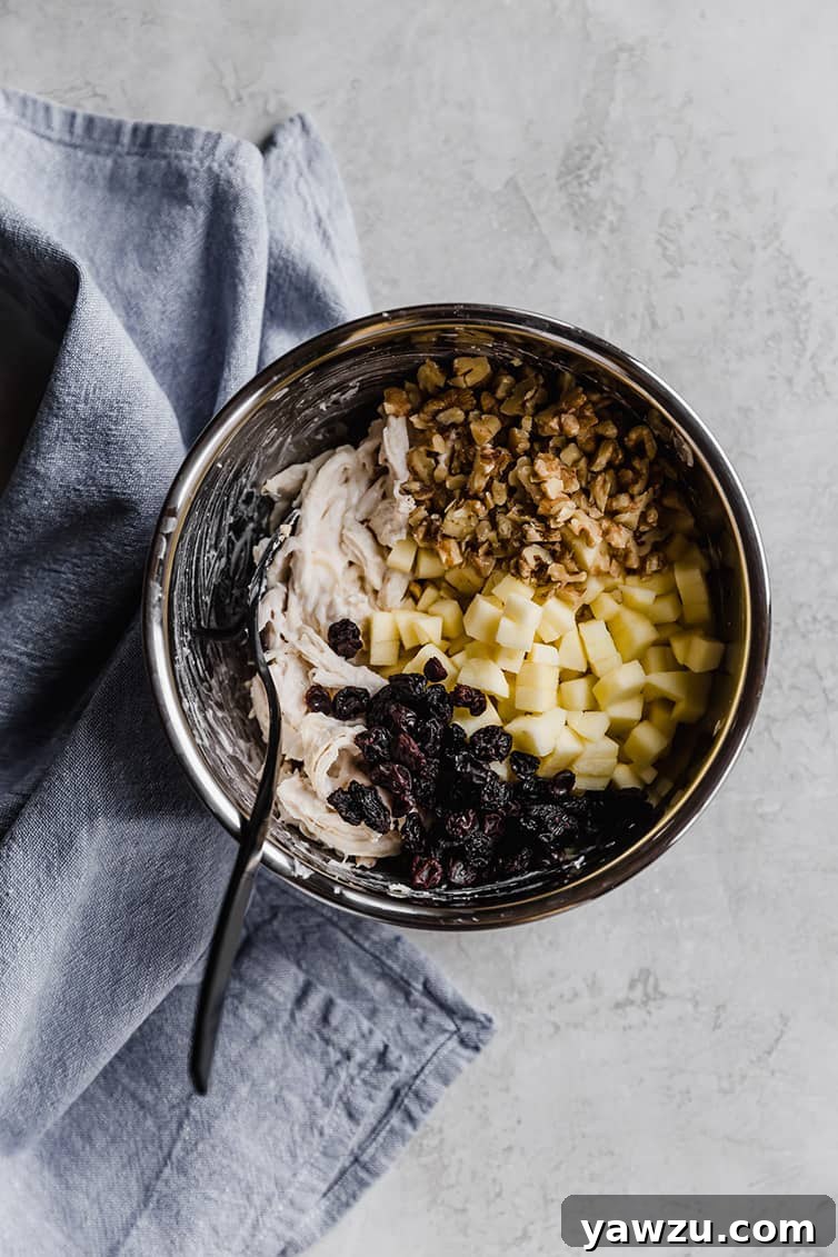 A mixing bowl with all of the ingredients for chicken salad.