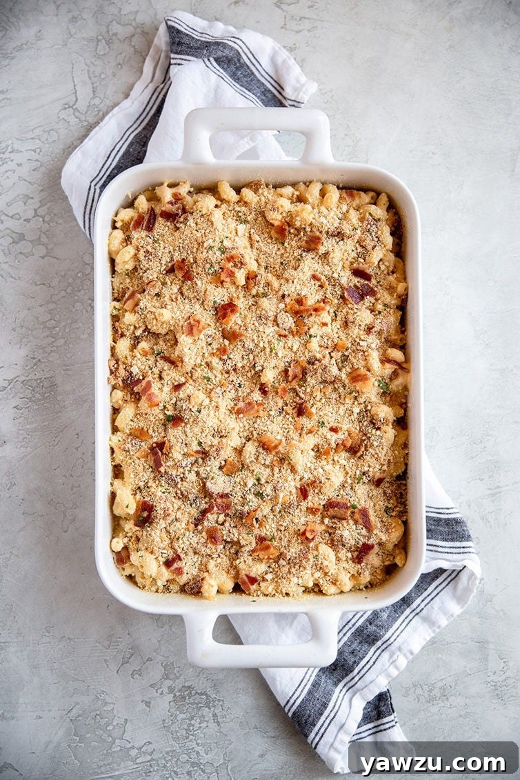 A casserole dish filled with unbaked mac and cheese, generously topped with a crunchy Ritz and bacon mixture, ready for the oven.