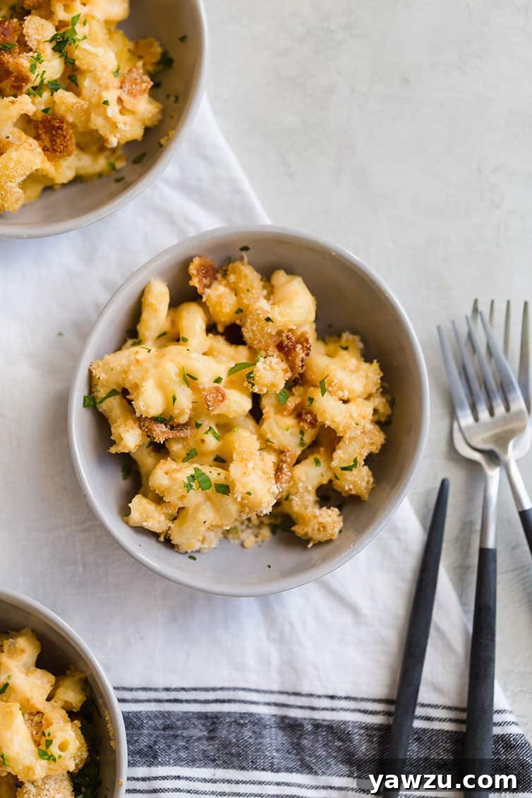 An overhead view of a single serving bowl of ultimate baked mac and cheese, garnished with fresh parsley and ready to eat.