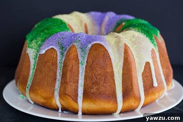 A beautifully glazed and decorated King Bundt Cake, showcasing the festive Mardi Gras colors on a simple white background.