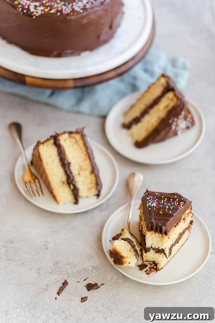 Three slices of yellow cake with chocolate frosting on plates.