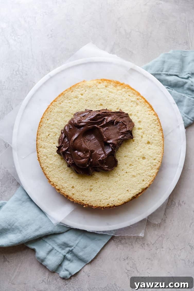 A layer of yellow cake with a dollop of chocolate frosting on top.