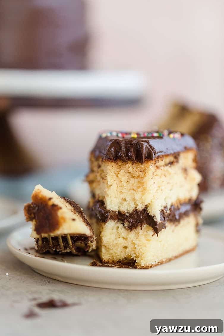 A slice of yellow cake on a plate with a forkful taken out of the front.