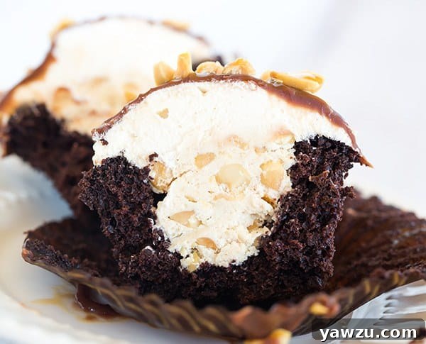 A close-up of a Snickers cupcake cut in half, revealing the nougat filling.
