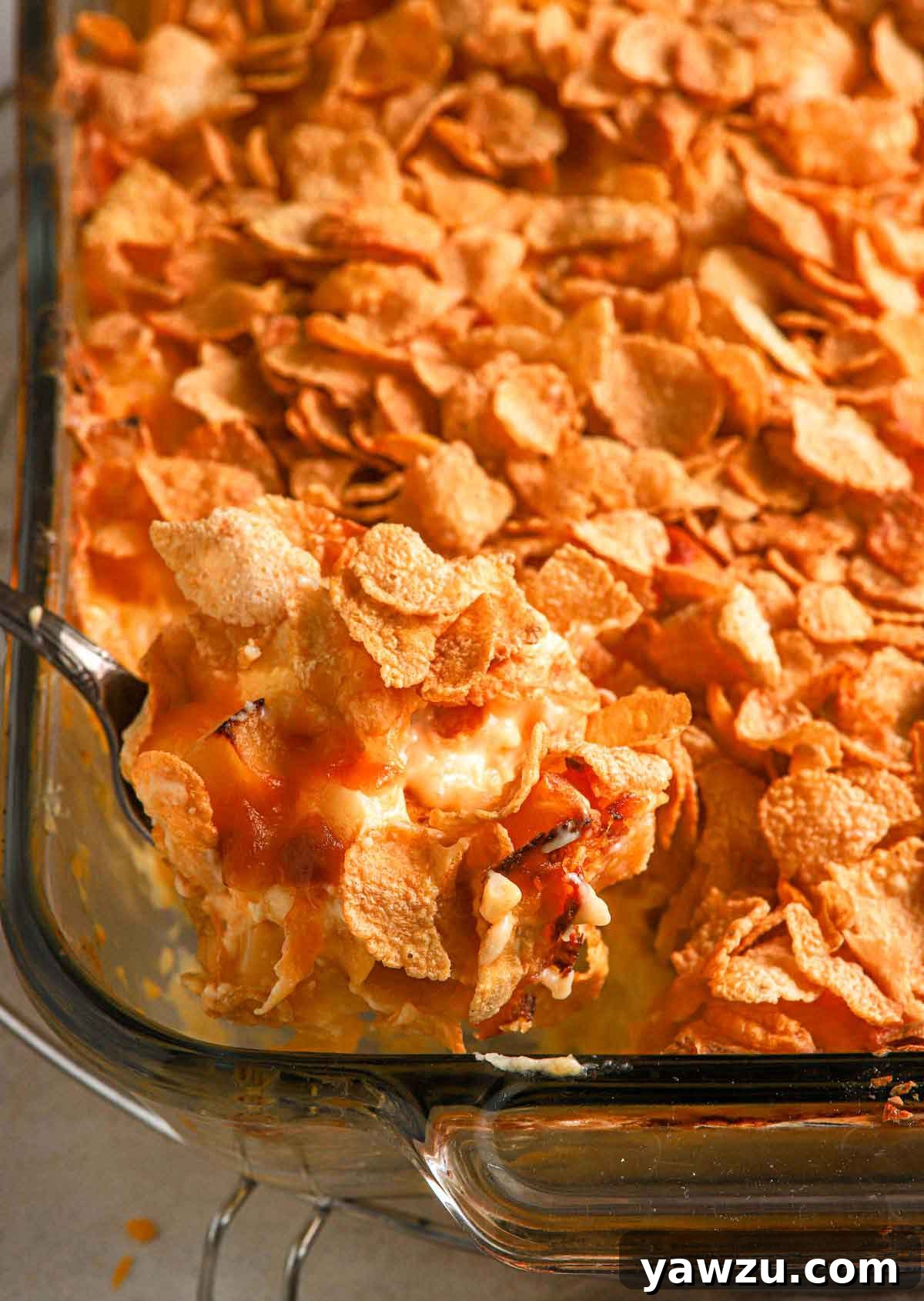 Serving spoon scooping out cheesy potato casserole from a baking dish.