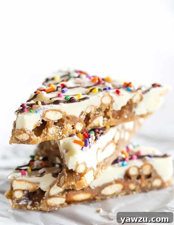 Colorful Pretzel Bark with white chocolate and rainbow sprinkles, drizzled with dark chocolate, ready to be broken and served.