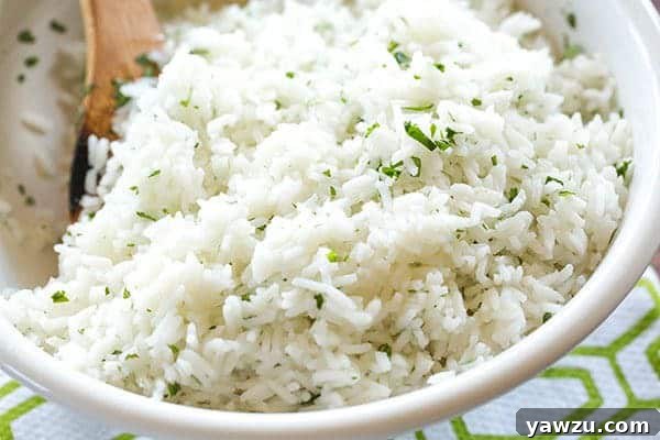 A close-up shot of the perfectly cooked cilantro-lime rice in a white bowl, showcasing its separated grains and vibrant green specks of cilantro.