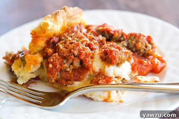Close-up of a square slice of deep dish biscuit pizza, showcasing the thick, golden biscuit crust, gooey melted cheese, and savory toppings.