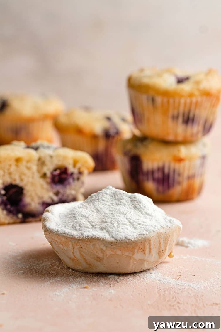 A scoop of baking powder in front of blueberry muffins.