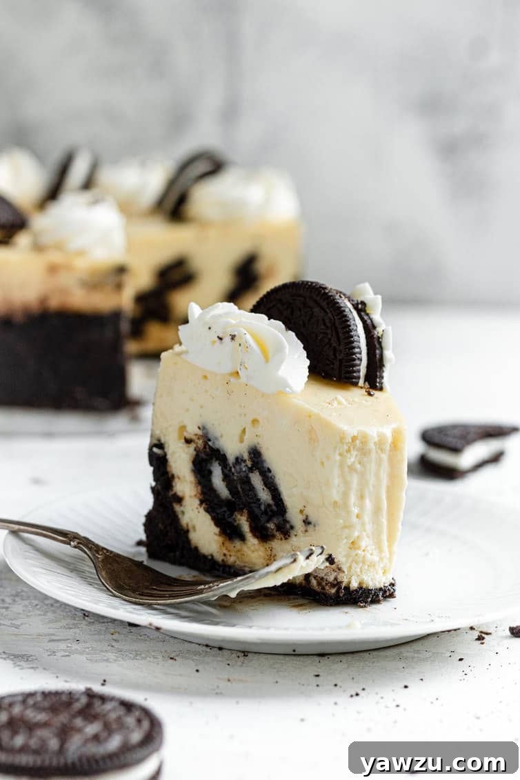 A delectable slice of Oreo cheesecake served on a pristine white plate with a fork, emphasizing its distinct layers and chunky cookie filling.