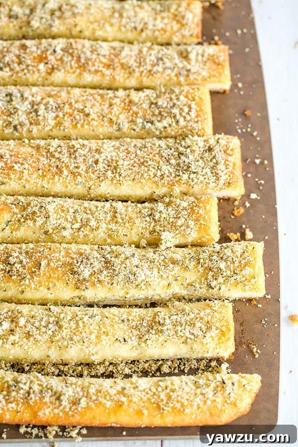 Close-up of freshly baked Pizza Hut style breadsticks, glistening with butter and seasonings, ready for dipping.