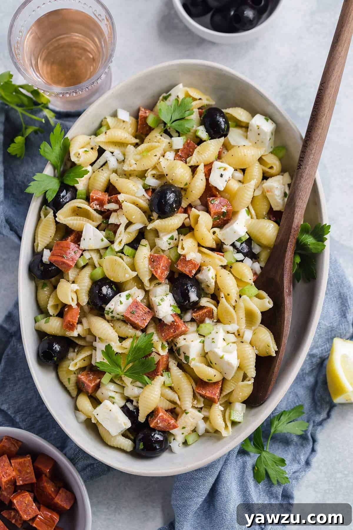 A vibrant bowl of Italian pasta salad, artfully arranged, with a glass of red wine casually placed next to it, evoking a relaxed summer dining experience.