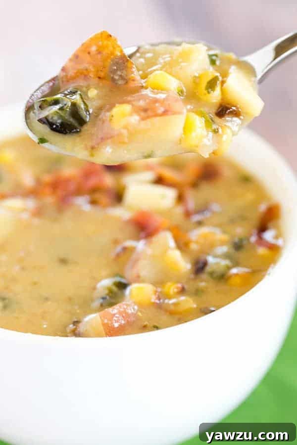 A close-up shot of the finished Roasted Corn and Poblano Chowder, garnished with crispy bacon bits and crumbled queso fresco, inviting to taste.