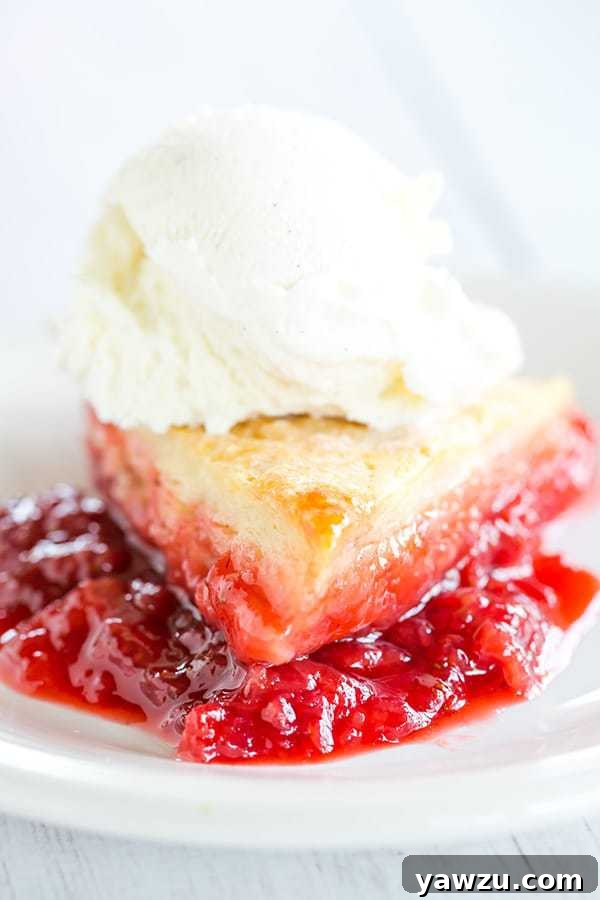 Close-up of baked strawberry cobbler, showing the bubbly red jam peeking through the golden biscuit topping.